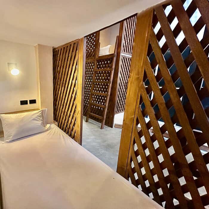 Lámpara de pared y cama en habitación con decoración en madera y elementos naturales en Masaya, alojamiento en Nicaragua con estilo moderno y confort.