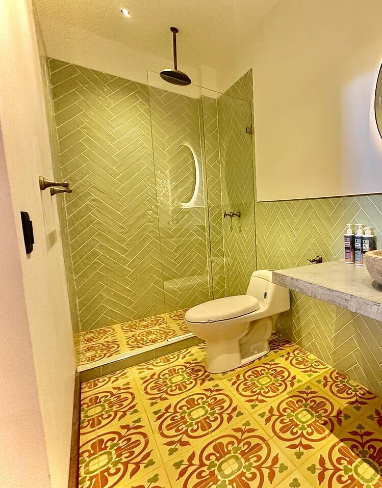 Lujoso baño en Masaya, con baldosas de diseño tradicional, lavabo de piedra, espejo con iluminación ambiental y ducha moderna para una experiencia auténtica y confortable en el corazón de Nicaragua.