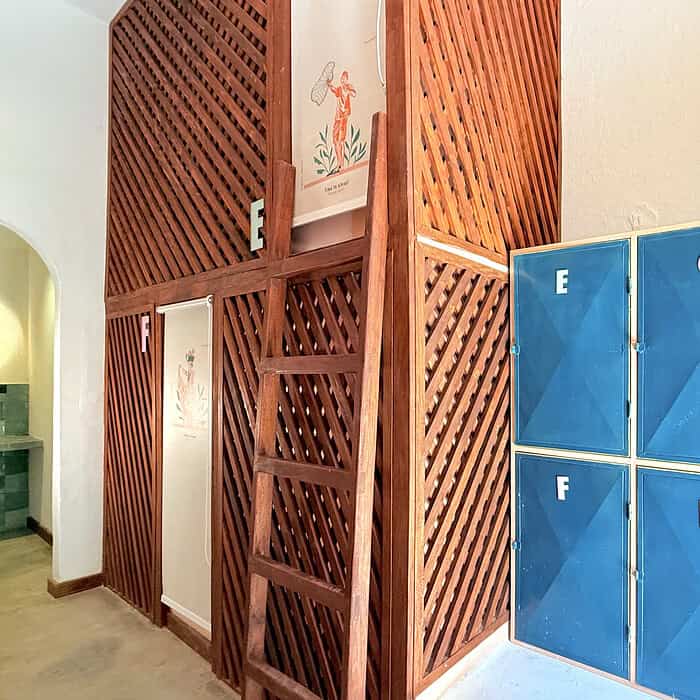 Puertas de casilleros azules con letras en un ambiente interior de estilo tropical, con estructura de madera y detalles decorativos que evocan la cultura de Masaya, Nicaragua.