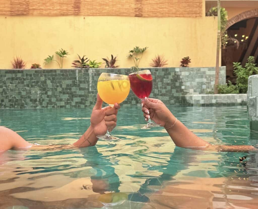 Brindis en piscina con cócteles coloridos en un ambiente relajante y elegante.