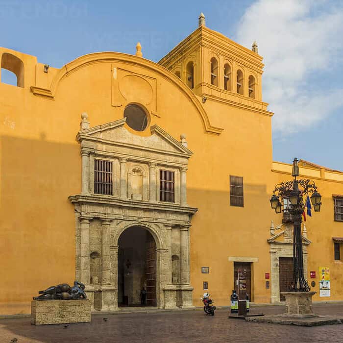 Puerta de una iglesia colonial con fachada amarilla y detalles en piedra en un entorno urbano.