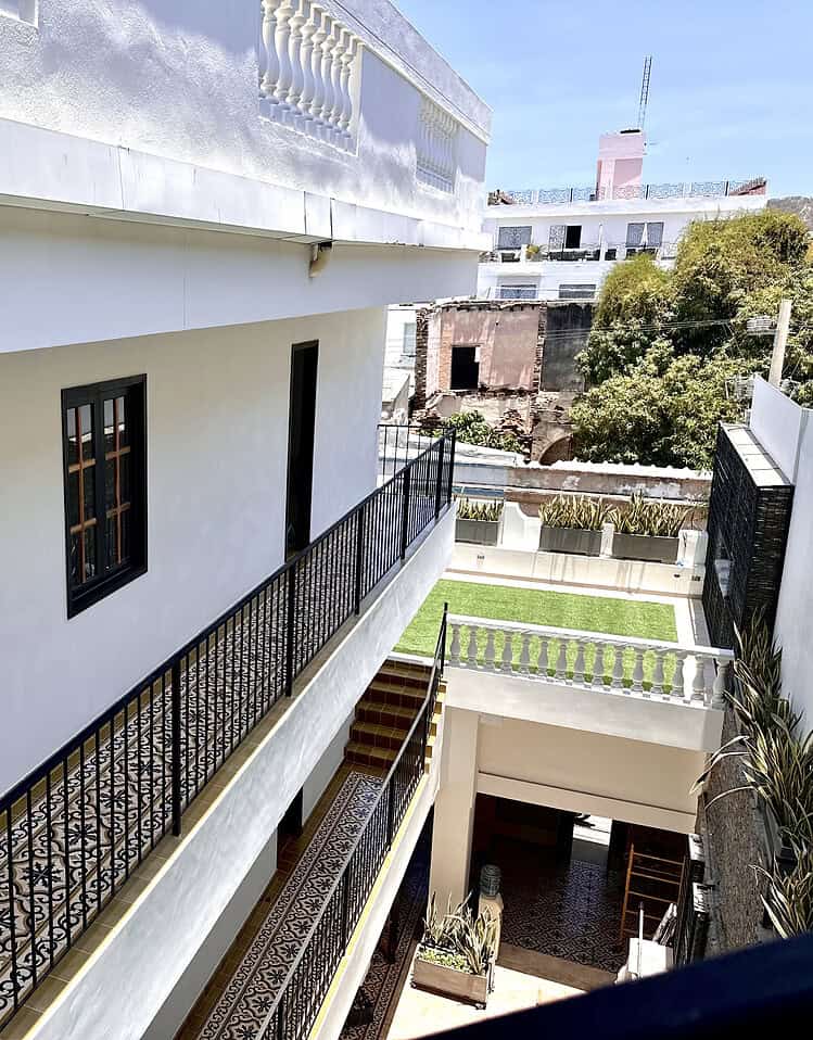 Puerta de entrada en un balcón de hotel boutique Masaya, con barandilla de hierro y vista a áreas verdes y edificios cercanos en un entorno urbano.
