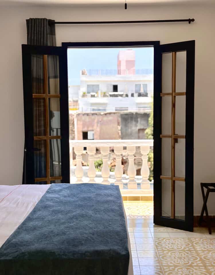 Puertas de balcón abiertas en habitación con vista a la ciudad.