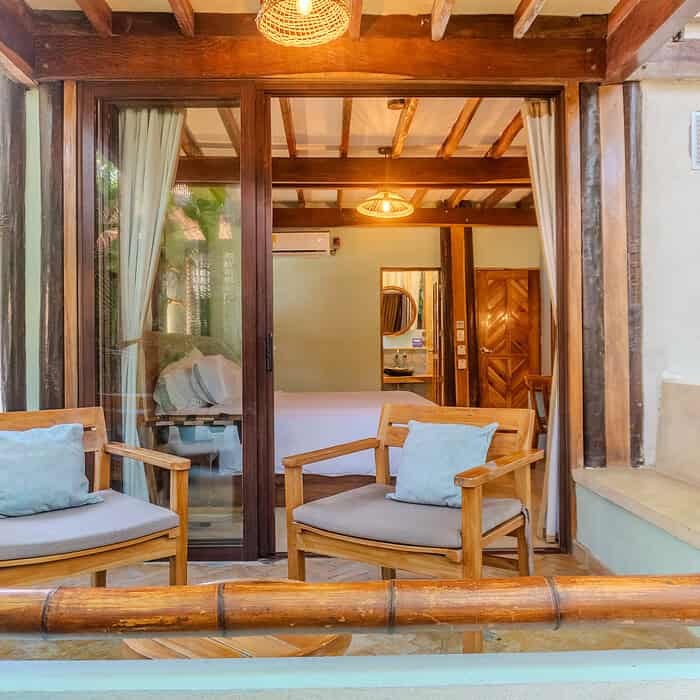 Zona de descanso con sillones de madera y cojines en un ambiente natural y acogedor de M.