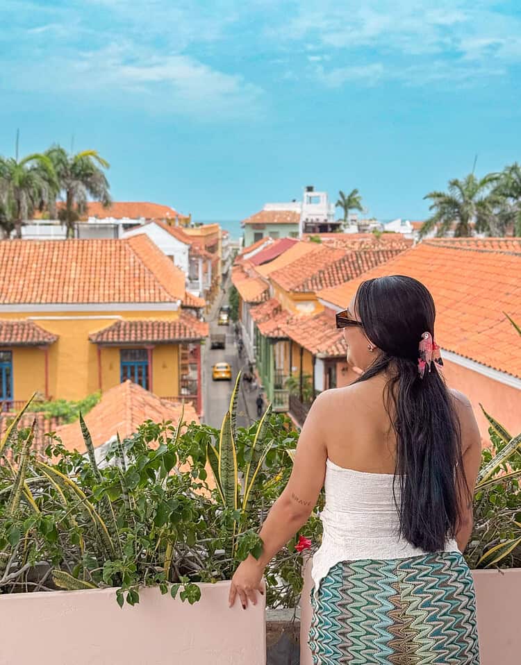 M mujer disfrutando de la vista de casas con techos de teja en un día soleado.