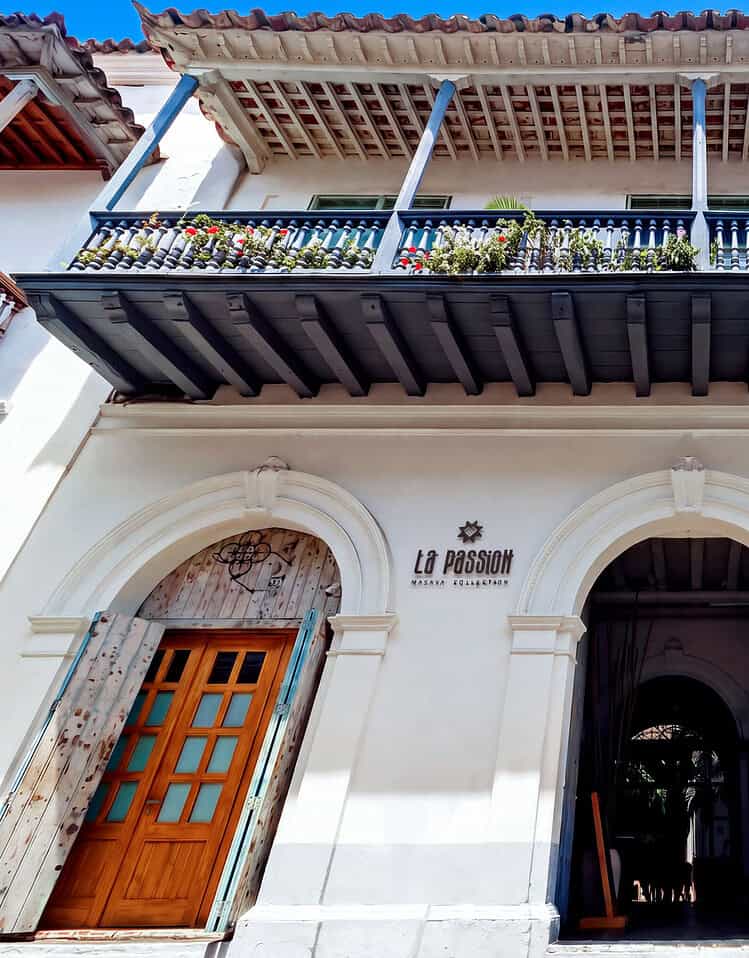 Edificio colonial con balcón de hierro forjado y puertas de madera en M.