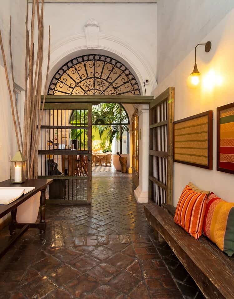 Vestíbulo de estilo colonial en M con paredes blancas, mobiliario de madera y detalles decorativos coloridos.