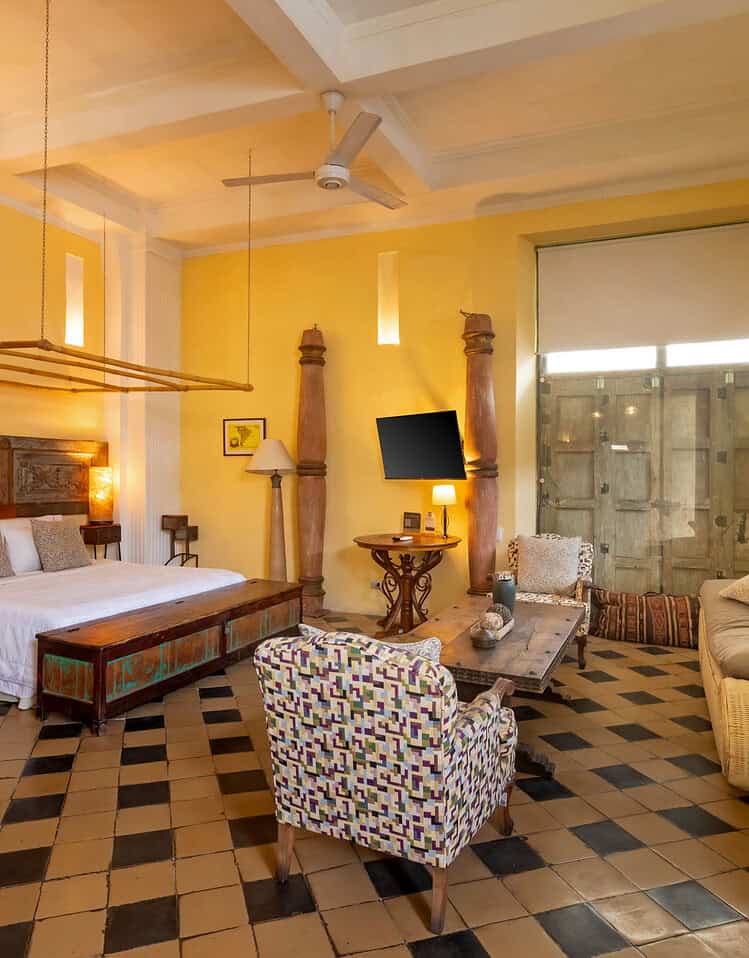 Habitación de hotel con cama grande, sillón y decoración cálida en M.