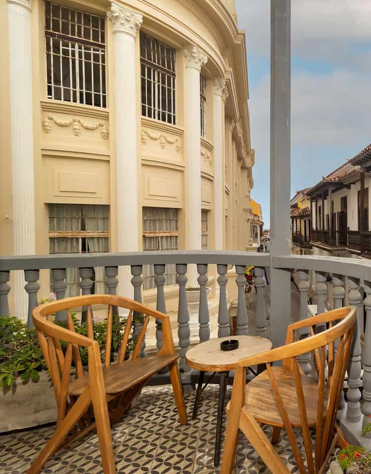 Vista de balcón con muebles de madera y arquitectura colonial en un día soleado.