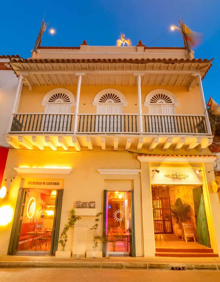 Fachada de un hotel boutique en la noche con iluminación cálida y detalles arquitectónicos tradicionales en un entorno urbano.