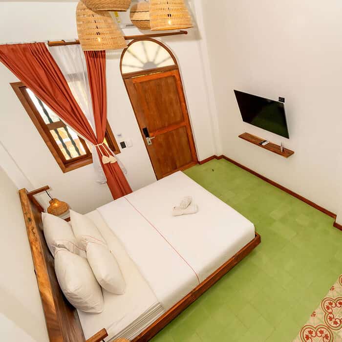 Vista aérea de una habitación en M con cama, televisión y decoración cálida.