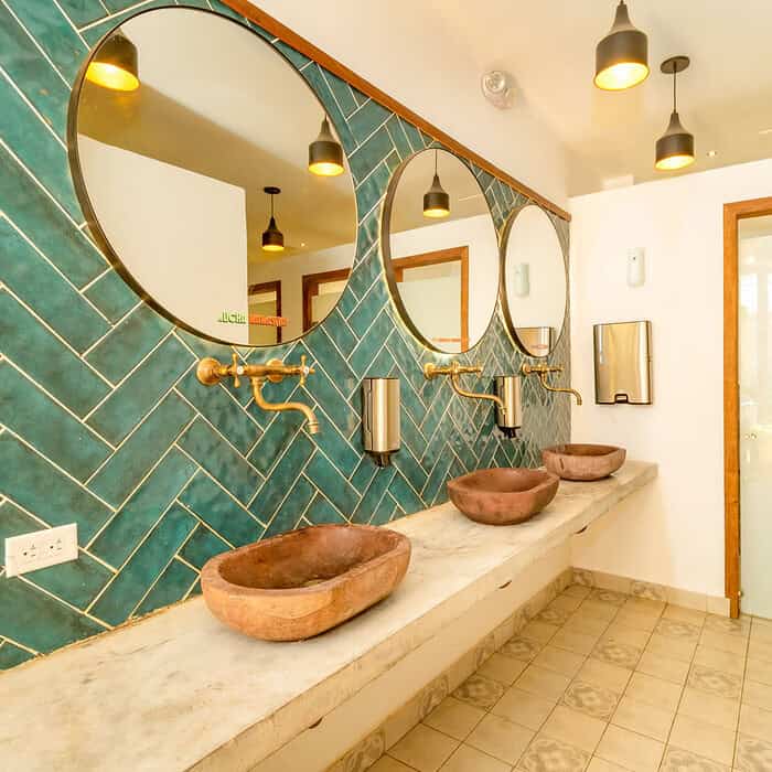 Baño moderno con lavabos de piedra y espejos redondos en M, en un ambiente luminoso y elegante.
