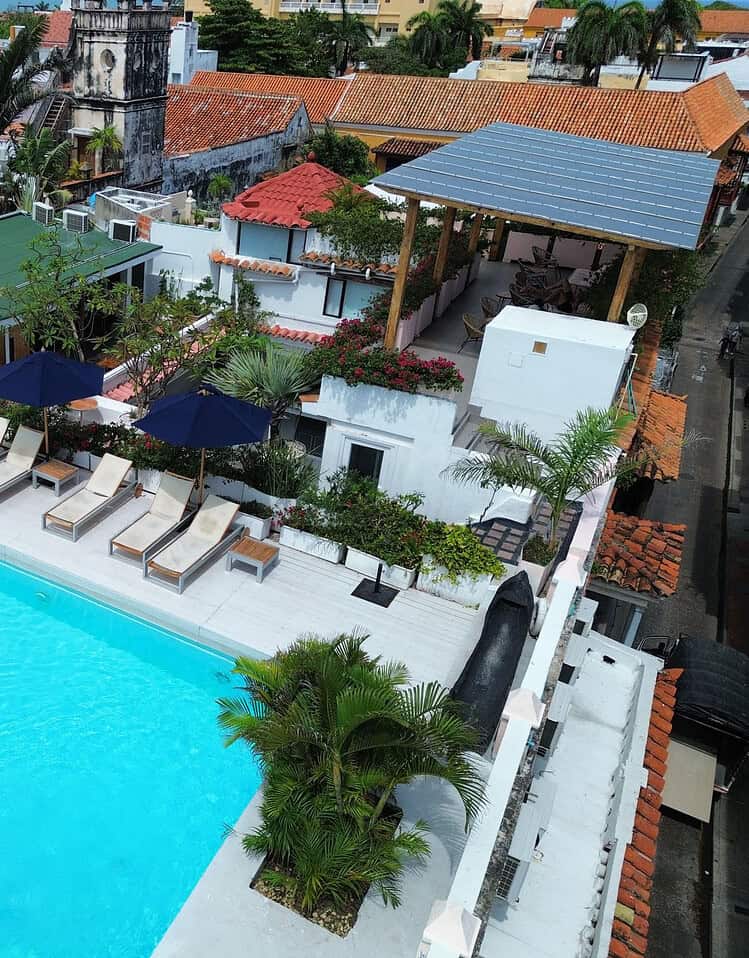 Piscina en la azotea con tumbonas, sombrillas y áreas verdes en un hotel boutique de M.